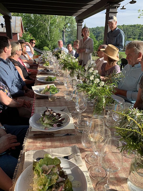 Long table set with wine and salad. Diana McCargo gives a toast